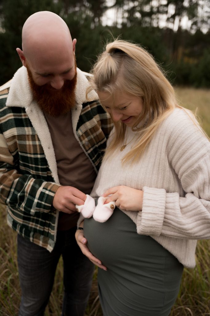 werdende Eltern mit Babyschuhe auf Babybauch