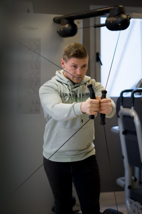 Junger Mann trainiert mit einem Kabelzuggerät im Fitnessstudio.