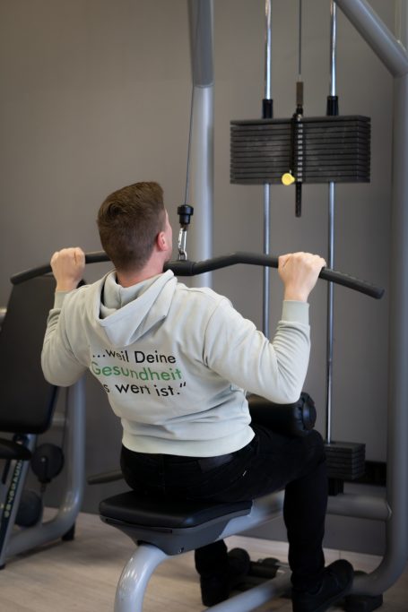 Mann trainiert im Fitnessstudio an einer Latissimus-Maschine.