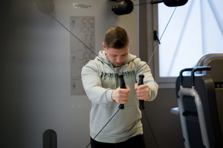 Mann trainiert an einem Kabelzuggerät im Fitnessstudio.